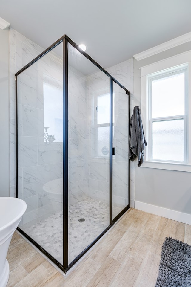 bathroom with a shower stall, wood finished floors, crown molding, and baseboards