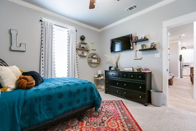 bedroom with light carpet, visible vents, a ceiling fan, and ornamental molding
