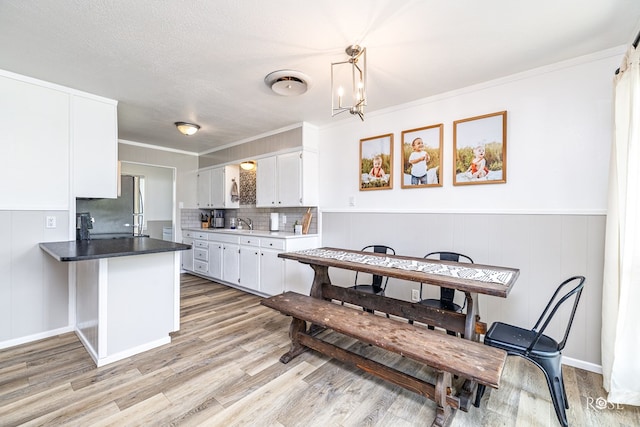 412 E Holmes Ave, Bronte, TX 76933 - kitchen with freestanding refrigerator, white cabinetry, light wood finished floors, decorative backsplash, and a peninsula