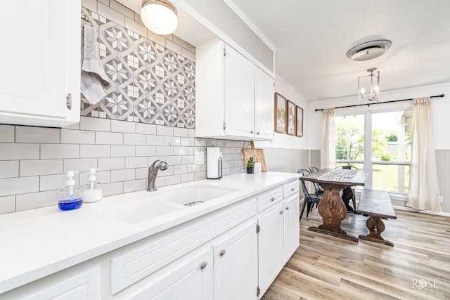 412 E Holmes Ave, Bronte, TX 76933 - kitchen featuring light countertops, white cabinetry, light wood-type flooring, wainscoting, and decorative backsplash