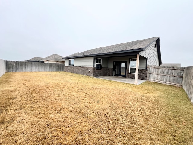 rear view of house featuring a yard and a patio