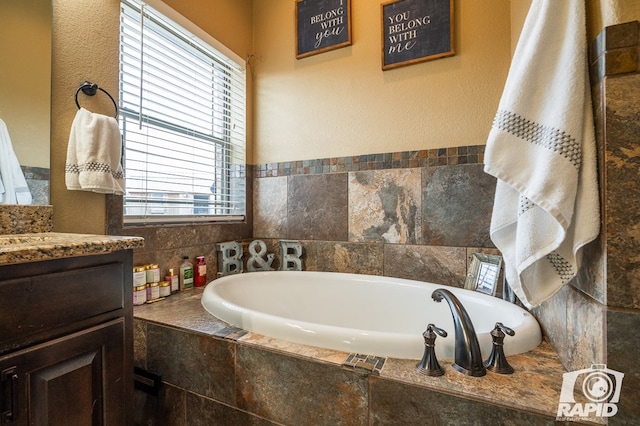 bathroom featuring vanity and tiled tub