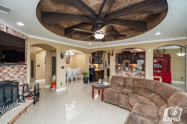 living room featuring ornamental molding, ceiling fan with notable chandelier, a fireplace, and a tray ceiling