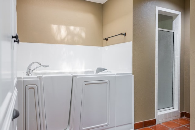 3705 Gemini Dr, San Angelo, TX 76903 - bathroom with tile patterned floors, a textured wall, a shower stall, and washer / dryer