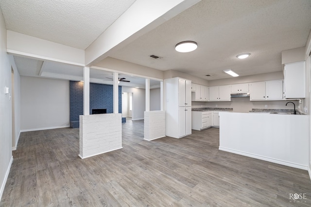 kitchen featuring white cabinetry, a textured ceiling, and a fireplace