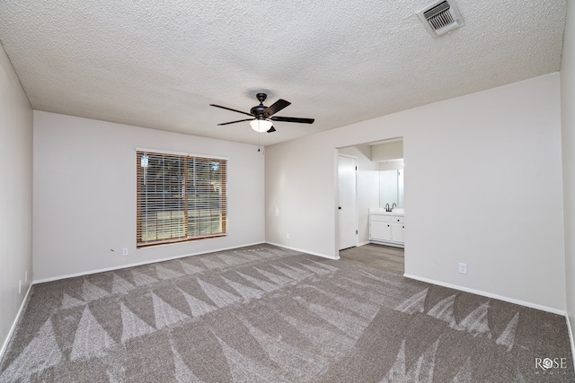 carpeted spare room featuring ceiling fan, sink, and a textured ceiling