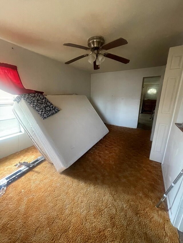 unfurnished bedroom featuring dark carpet and ceiling fan