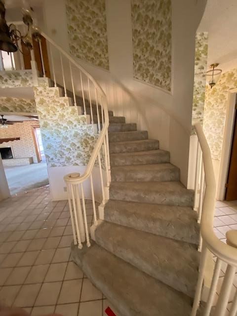 stairway featuring tile patterned flooring and a high ceiling