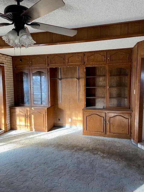 carpeted spare room featuring a textured ceiling, ceiling fan, and wood walls