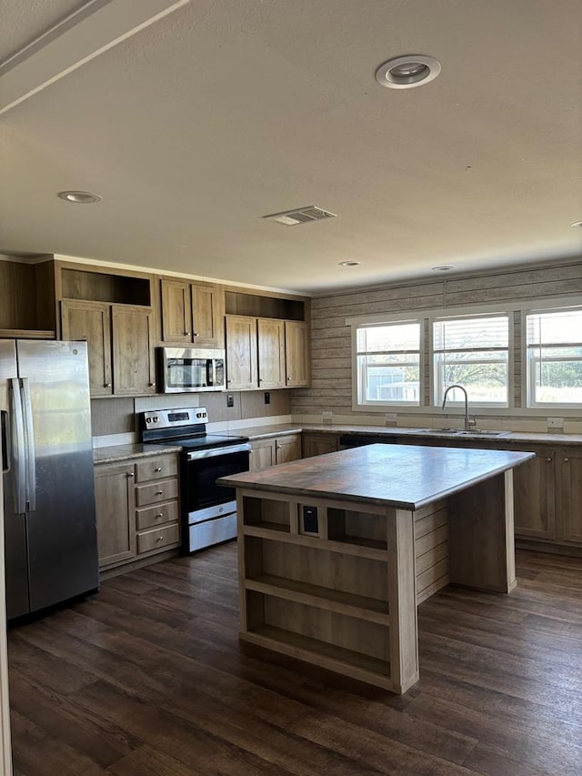 kitchen with stainless steel appliances, dark hardwood / wood-style floors, sink, and a kitchen island