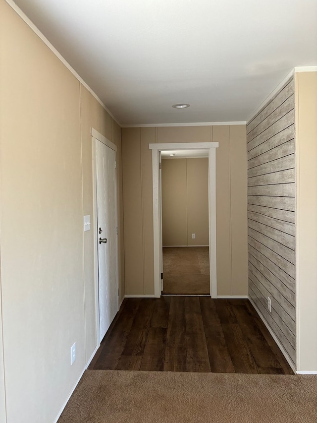 hallway featuring ornamental molding and dark colored carpet