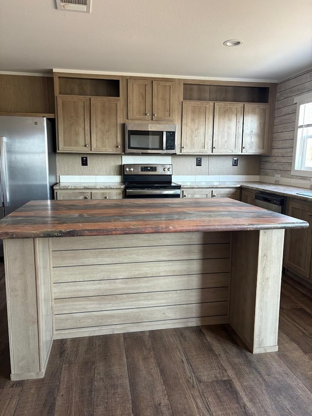 kitchen with butcher block countertops, dark wood-type flooring, stainless steel appliances, and a kitchen island