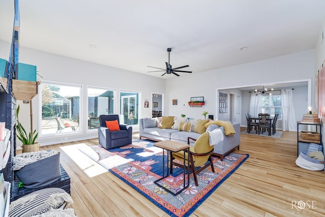 living room featuring a wealth of natural light, light hardwood / wood-style flooring, and ceiling fan with notable chandelier