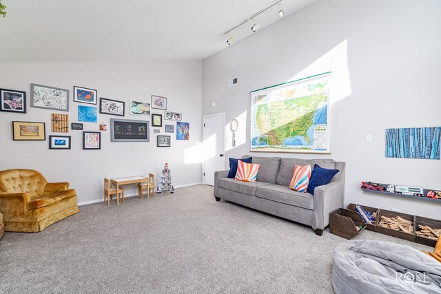 living room featuring track lighting, vaulted ceiling, and carpet