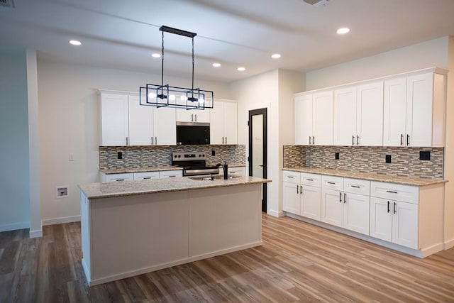 kitchen featuring white cabinetry, light stone countertops, stainless steel electric range oven, an island with sink, and pendant lighting