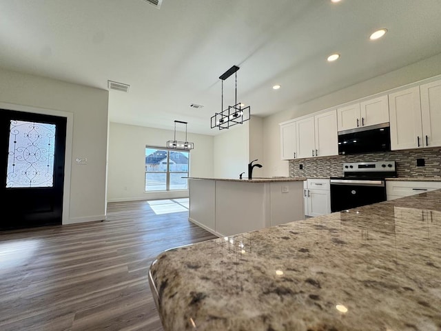 kitchen with pendant lighting, backsplash, stainless steel range with electric cooktop, white cabinetry, and an island with sink