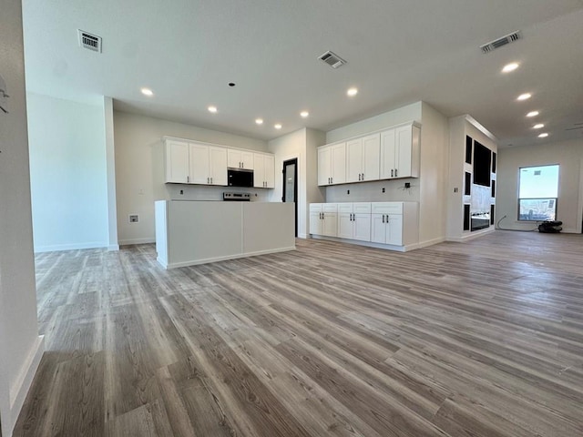 kitchen with visible vents, white cabinetry, and open floor plan