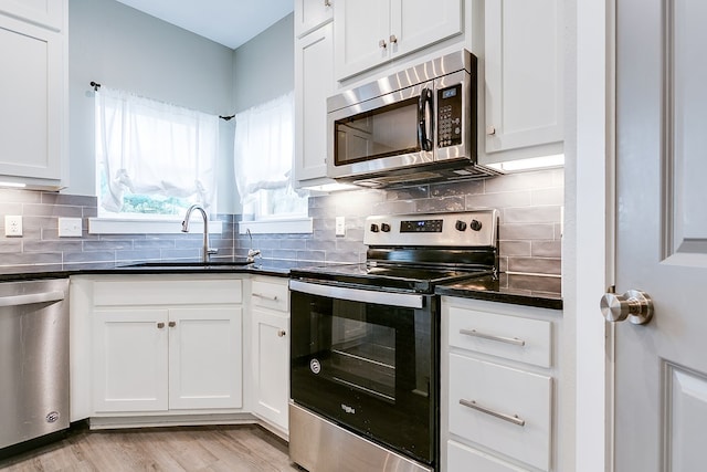 kitchen featuring stainless steel appliances, sink, white cabinets, and light wood-type flooring