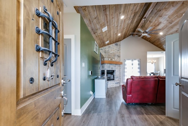 living room with a stone fireplace, wood ceiling, lofted ceiling with beams, dark hardwood / wood-style flooring, and ceiling fan with notable chandelier