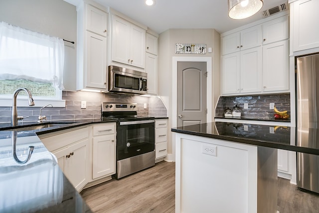 kitchen featuring sink, light hardwood / wood-style flooring, stainless steel appliances, a center island, and white cabinets