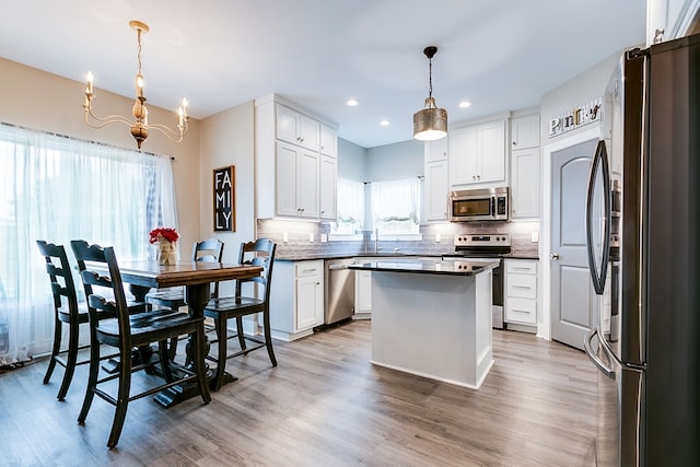 kitchen featuring sink, hanging light fixtures, a kitchen island, stainless steel appliances, and white cabinets