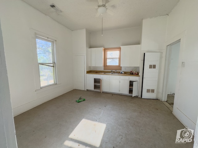 901 S Walnut St, Brady, TX 76825 - kitchen with white cabinetry, a sink, a textured ceiling, and ceiling fan