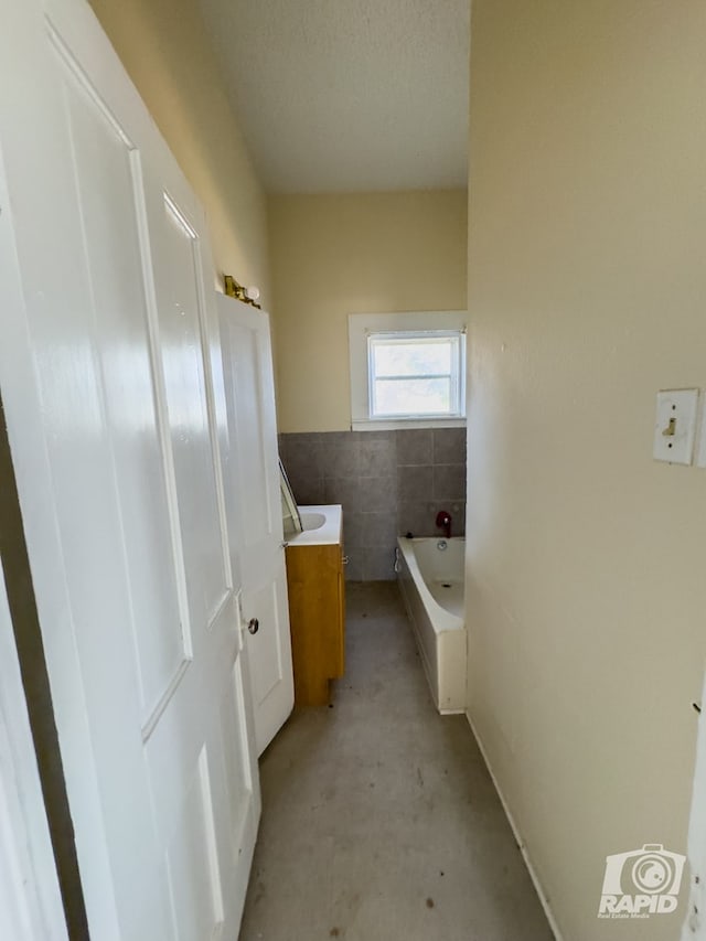901 S Walnut St, Brady, TX 76825 - full bathroom with unfinished concrete flooring, tile walls, a bath, and vanity