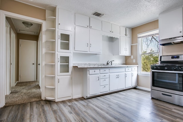1619 Spaulding St, San Angelo, TX 76905 - kitchen with stainless steel gas stove, open shelves, light wood-style floors, white cabinets, and a textured ceiling