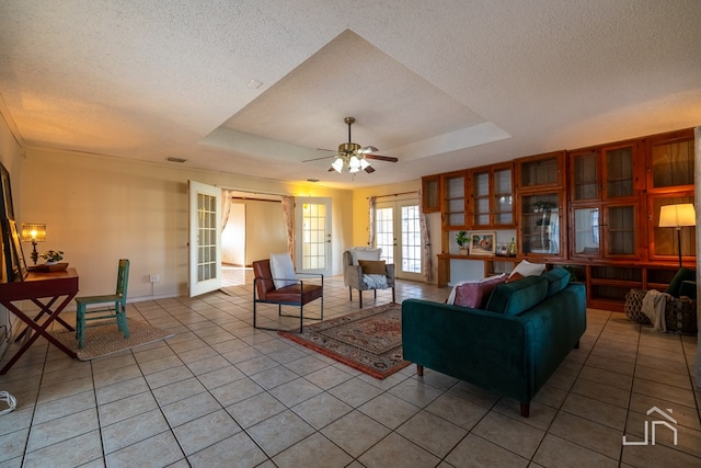 living room with light tile patterned floors, a tray ceiling, and french doors