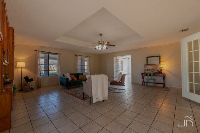 tiled living room with a raised ceiling and ceiling fan