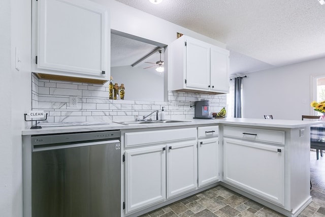 kitchen featuring a textured ceiling, stainless steel dishwasher, a sink, a peninsula, and backsplash