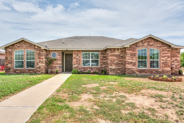ranch-style home featuring a front yard, a shingled roof, and brick siding
