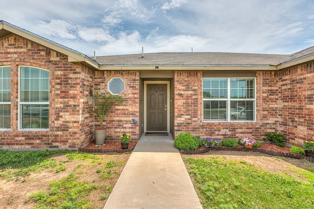 property entrance featuring brick siding and roof with shingles