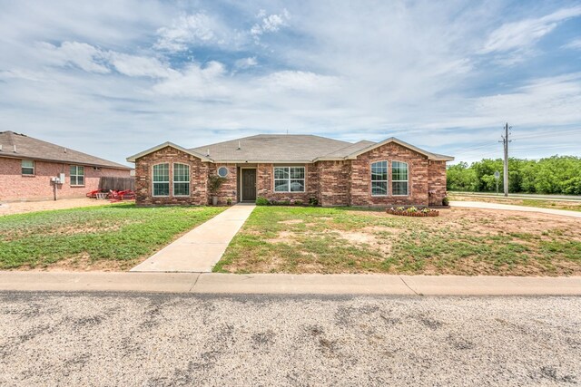 ranch-style house featuring roof with shingles, brick siding, and a front lawn