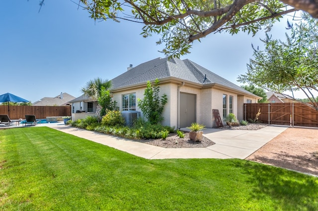 rear view of property with a fenced backyard, a yard, cooling unit, brick siding, and a patio area