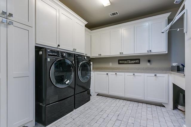 washroom with washing machine and dryer, cabinet space, brick floor, and visible vents