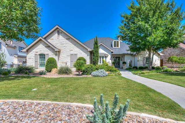 french provincial home featuring stone siding and a front lawn