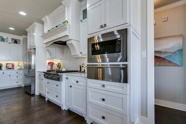 kitchen with a warming drawer, backsplash, stainless steel appliances, light countertops, and dark wood-style flooring