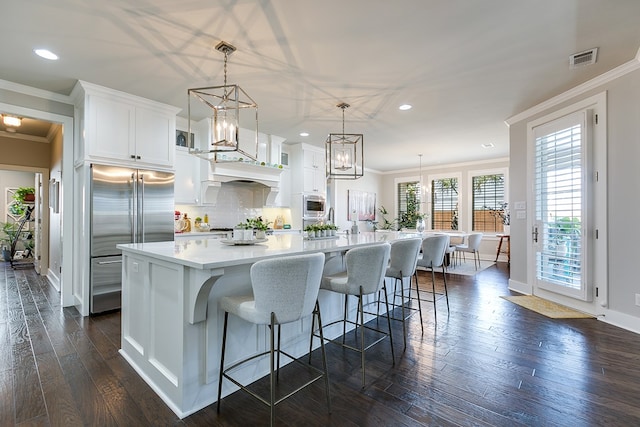 kitchen featuring visible vents, dark wood finished floors, light countertops, stainless steel built in fridge, and ornamental molding