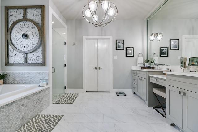 full bath with a garden tub, a stall shower, a notable chandelier, marble finish floor, and vanity