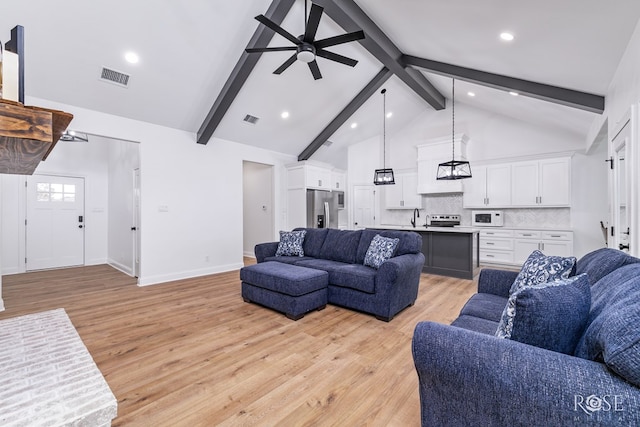 living room with high vaulted ceiling, light wood-type flooring, sink, and beam ceiling