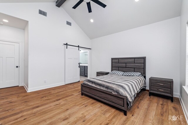 bedroom with hardwood / wood-style flooring, ceiling fan, beam ceiling, connected bathroom, and a barn door