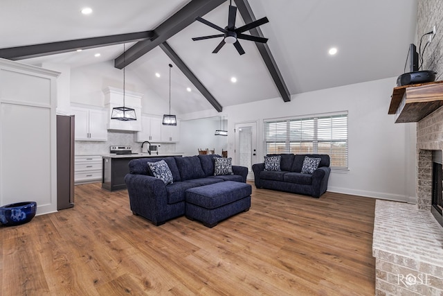 living room with beamed ceiling, a fireplace, high vaulted ceiling, and light wood-type flooring