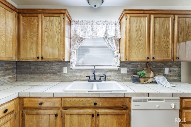 kitchen featuring tile countertops, white dishwasher, decorative backsplash, and a sink