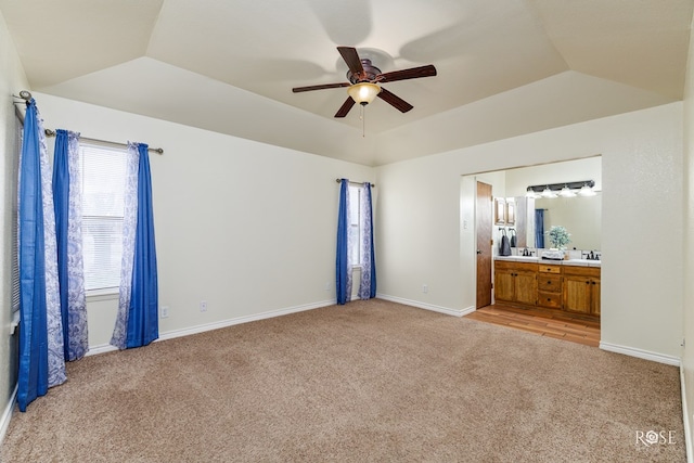 unfurnished bedroom with light carpet, a tray ceiling, and vaulted ceiling