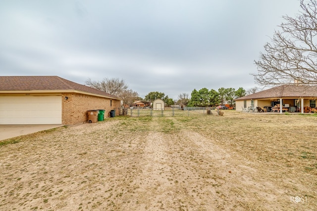 view of yard featuring a garage, fence, and an outdoor structure