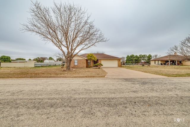 view of front of house with driveway, a garage, fence, a front lawn, and brick siding