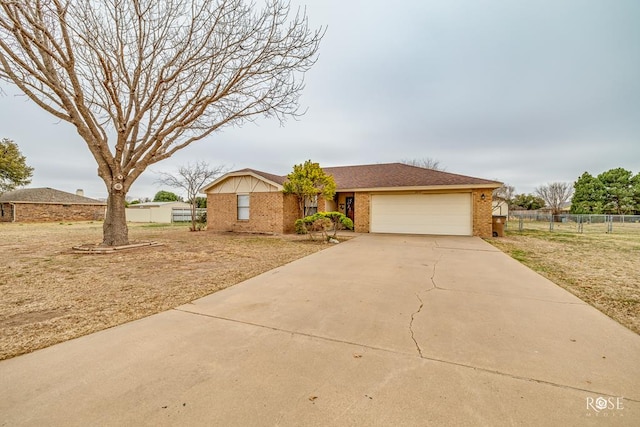 ranch-style home with concrete driveway, roof with shingles, an attached garage, fence, and brick siding