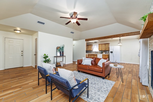 living room featuring visible vents, ceiling fan, light wood-style flooring, vaulted ceiling, and a fireplace