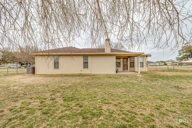 back of property with a lawn, fence, a chimney, and a patio